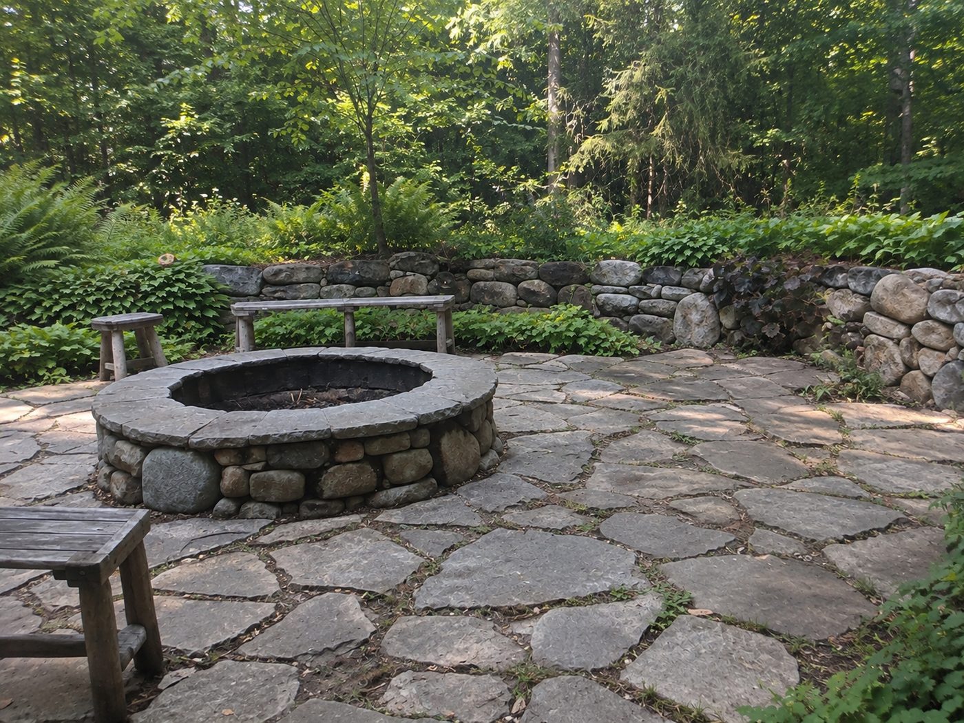 Before: a flagstone patio and stone fire pit in the woods, with weeds growing through the joints and worn mortar