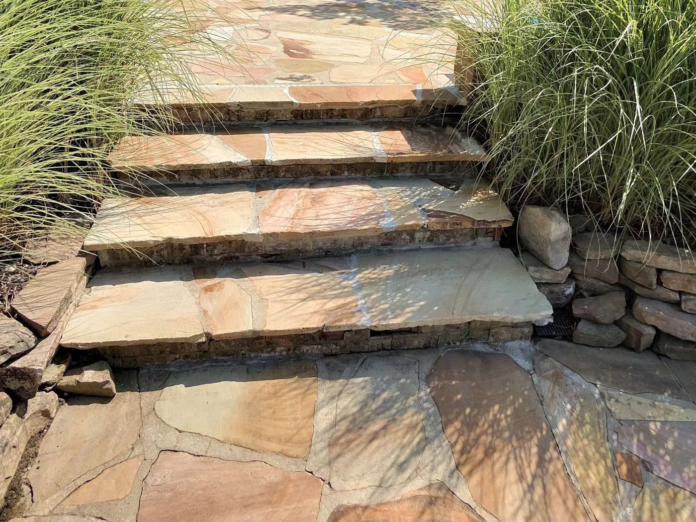 After: the repaired flagstone steps with fresh stone treads leading up to the finished patio and white brick home